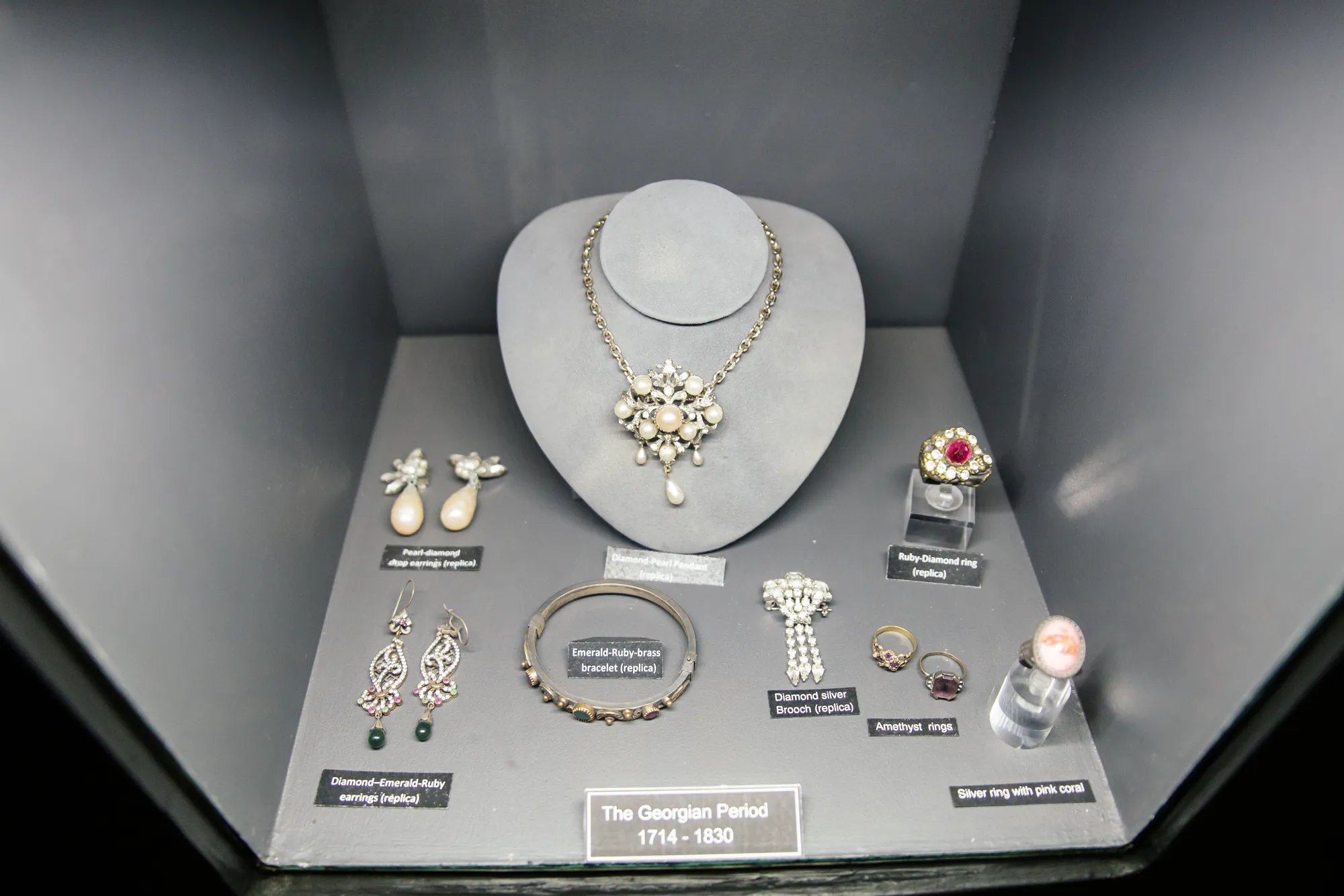The Georgian Period display case in the museum (1714 to 1830): Diamond-Pearl Pendant on a velvet neck form, Pearl-Diamond drop earrings, Diamond-Emerald-Ruby drop earrings, Emerald-Ruby brass bangle, Diamond Silver Brooch, Ruby-Diamond cluster ring, Amethyst rings and a Silver ring with pink coral
