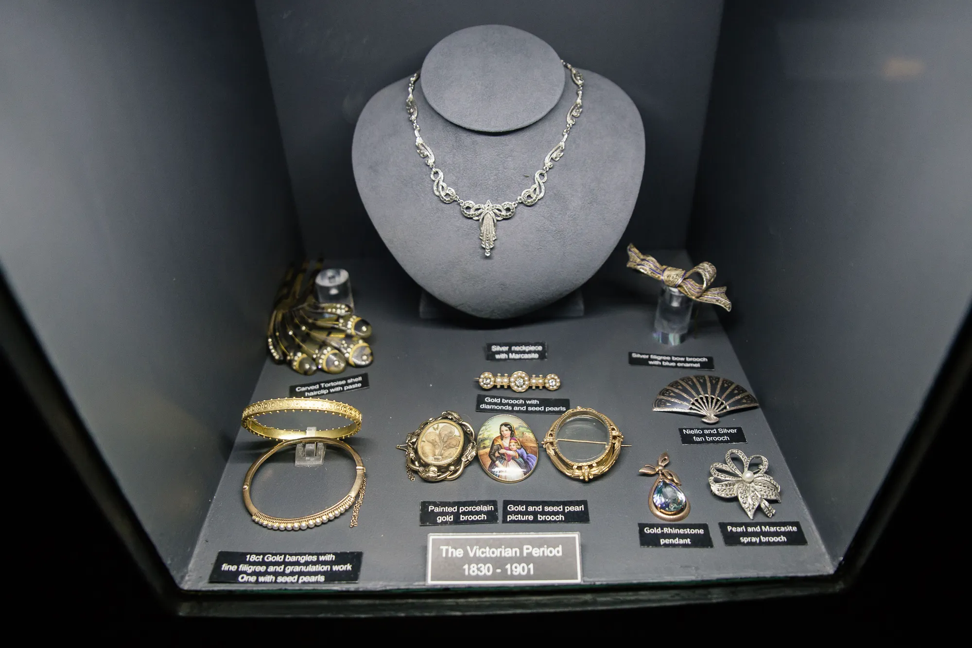 The Victorian Period display case in the museum (1830 to 1901): silver neckpiece with marcasite, 18ct gold bangles with filigree and seed pearls, painted-porcelain gold brooch, gold and seed-pearl picture brooch, niello and silver fan brooch, gold-rhinestone pendant and pearl-and-marcasite spray brooch